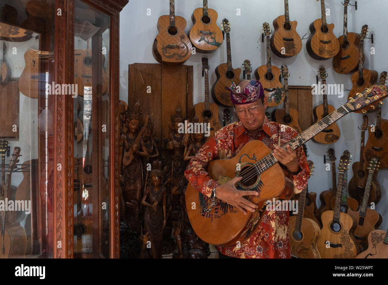 GIANYAR,BALI/INDONESIA-30 MAGGIO 2019: I Wayan Tuges, il proprietario del Tuges e mirtillo carving chitarra in Guwang, Gianyar Bali, possing con la sua carvi Foto Stock