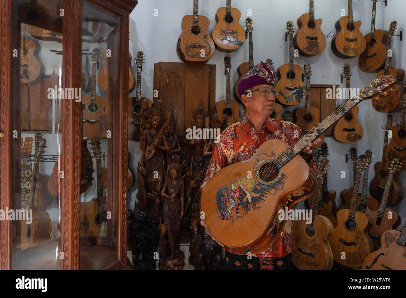 GIANYAR,BALI/INDONESIA-30 MAGGIO 2019: I Wayan Tuges, il proprietario del Tuges e mirtillo carving chitarra in Guwang, Gianyar Bali, possing con la sua carvi Foto Stock