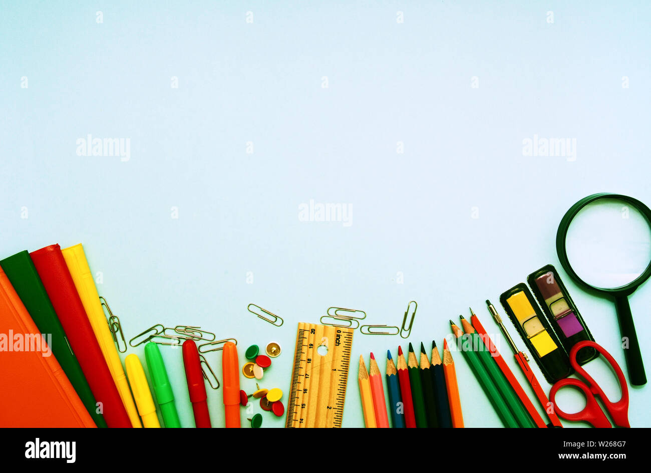 Scuola colorato forniture contro la luce sfondo blu con copia spazio. Si torna a scuola concetto, vista in pianta a croce per effetto del processo. Foto Stock
