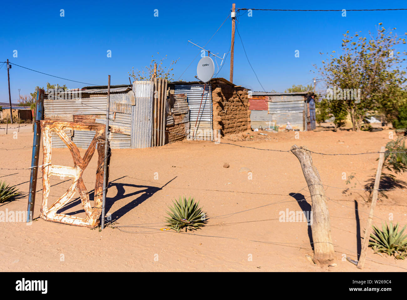 Home fatta da ferro corrugato fogli, con una grande antenna parabolica, in una cittadina alla periferia di Otjiwarongo, Namibia Foto Stock