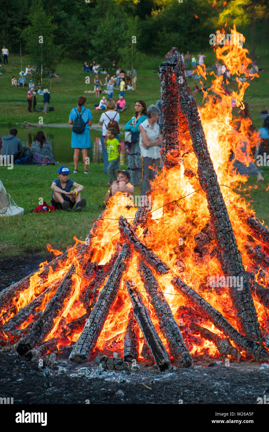 Le persone intorno a un falò in un insieme di strutture o in un parco, verticale Foto Stock