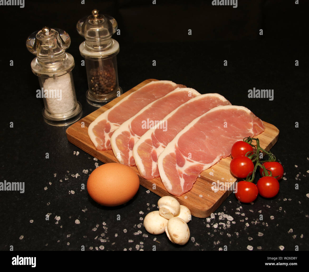 quattro fette di pancetta, uova, funghi e pomodori pronti a cucinare Foto Stock
