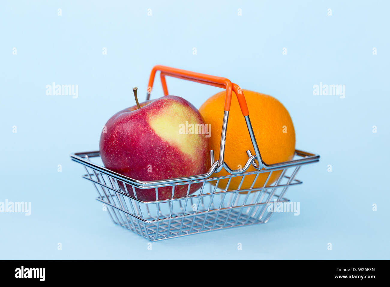Apple rosso e arancio in carrello su blu colore di sfondo Foto Stock