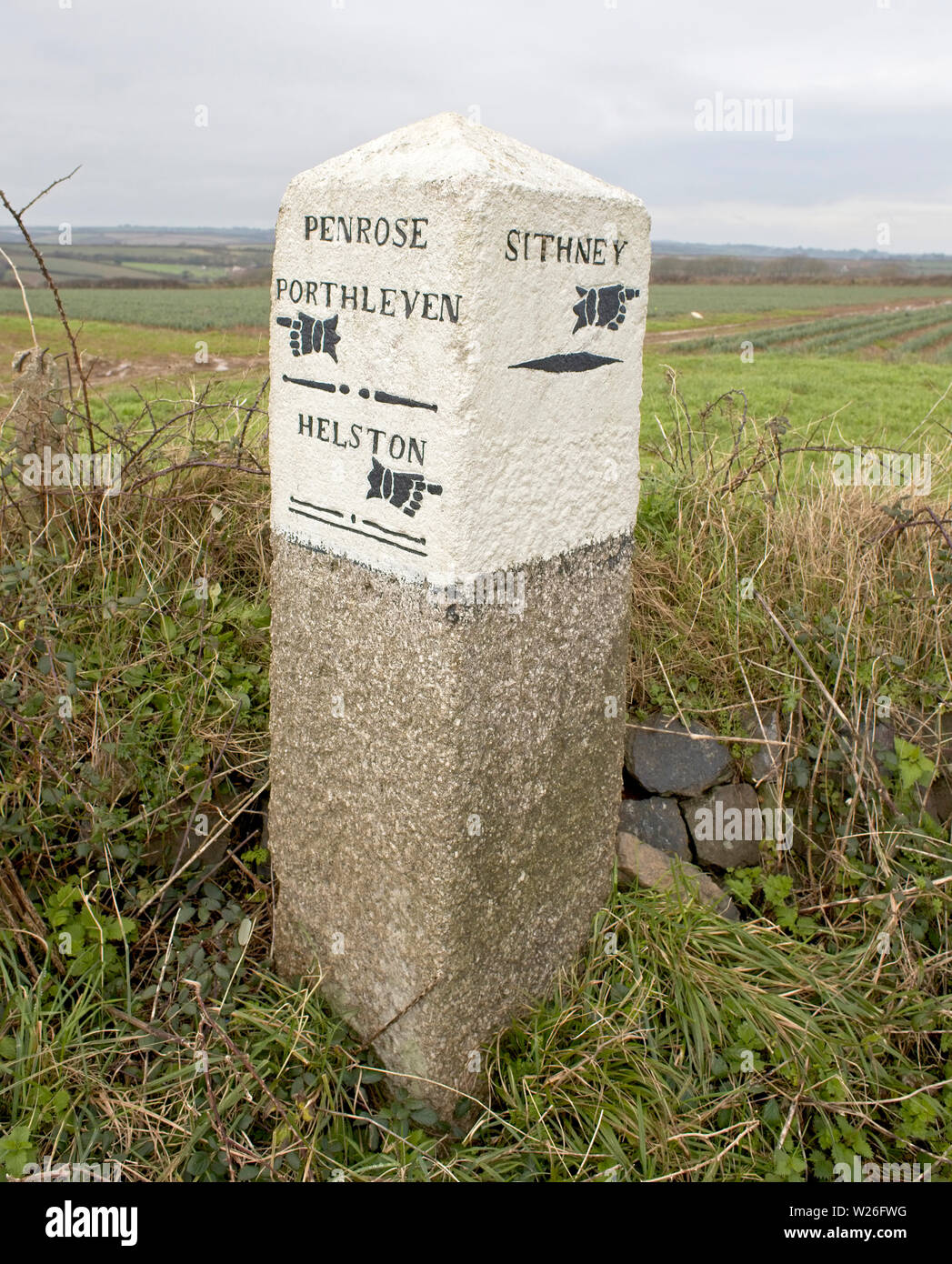Vecchia pietra miliare in corrispondenza di un incrocio stradale tra Helston e Porthleven, Cornwall, Inghilterra, Regno Unito. Foto Stock
