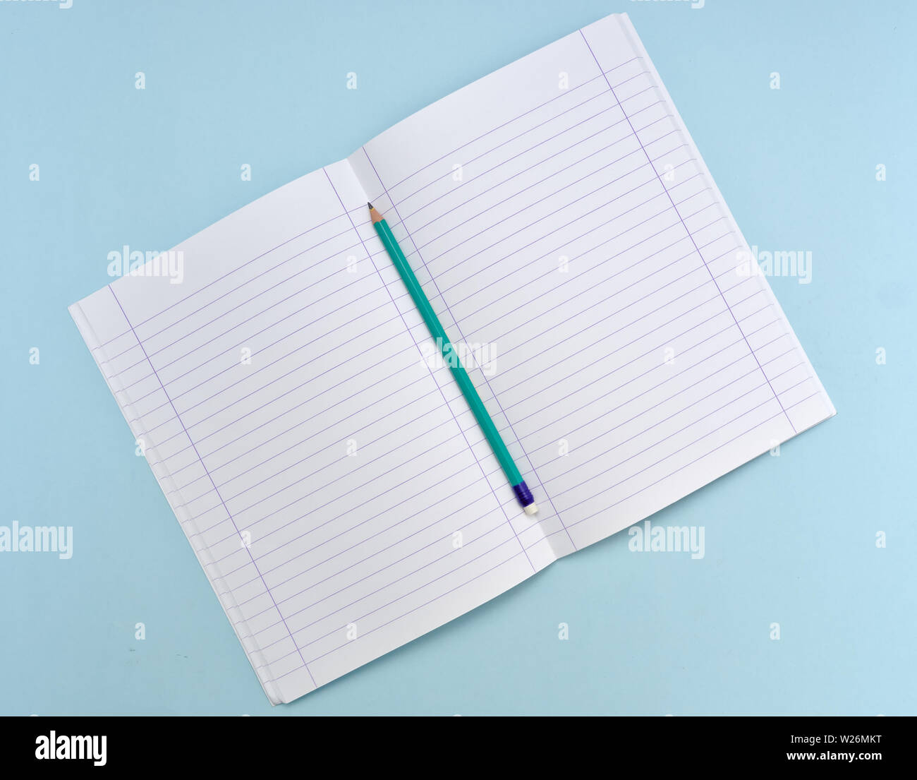 Aperta isolata notebook bianco rivestito con carta e matita verde su fondo azzurro. Foto Stock