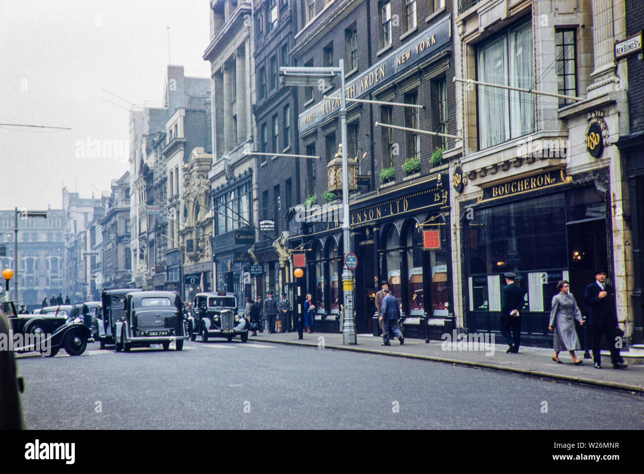 New Bond Street negli anni cinquanta, l'immagine mostra i gioiellieri J W Benson Ltd lungo con un annuncio pubblicitario per Elizabeth Arden sopra il negozio facciata. Il carrello di Hackney (London Black Cab Taxi) è visibile anche in una precedente incarnazione Beardmores e Austin FX3 sono stati i principali veicoli del giorno. Foto Stock