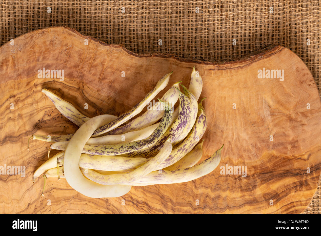 Organico giallo piatto di fagioli di cera pila sul tessuto di iuta e oliva legno taglio bordo dello sfondo. Foto Stock