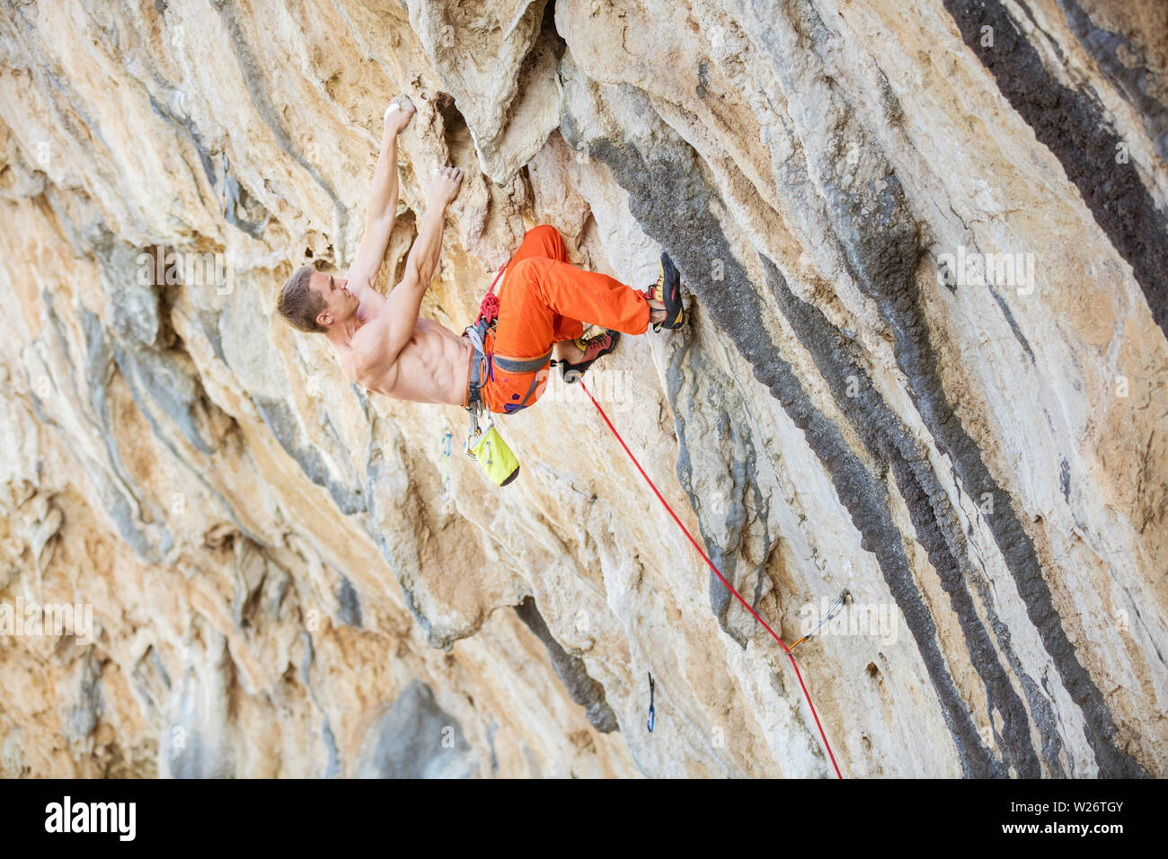 Giovani caucasici uomo climbing impegnativo percorso sulla rupe a strapiombo Foto Stock