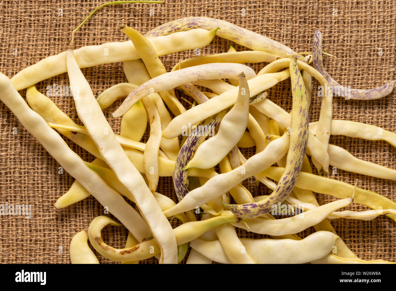 Organico giallo piatto di fagioli di cera pila sul tessuto di iuta sfondo. Foto Stock