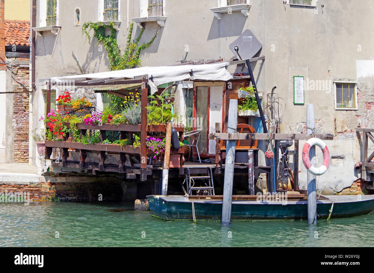 Casa su fondamenta S Angelo, l'isola della Giudecca, con una terrazza in legno sporgente oltre il canale coperto in una massa di colorati per le piante in vaso Foto Stock