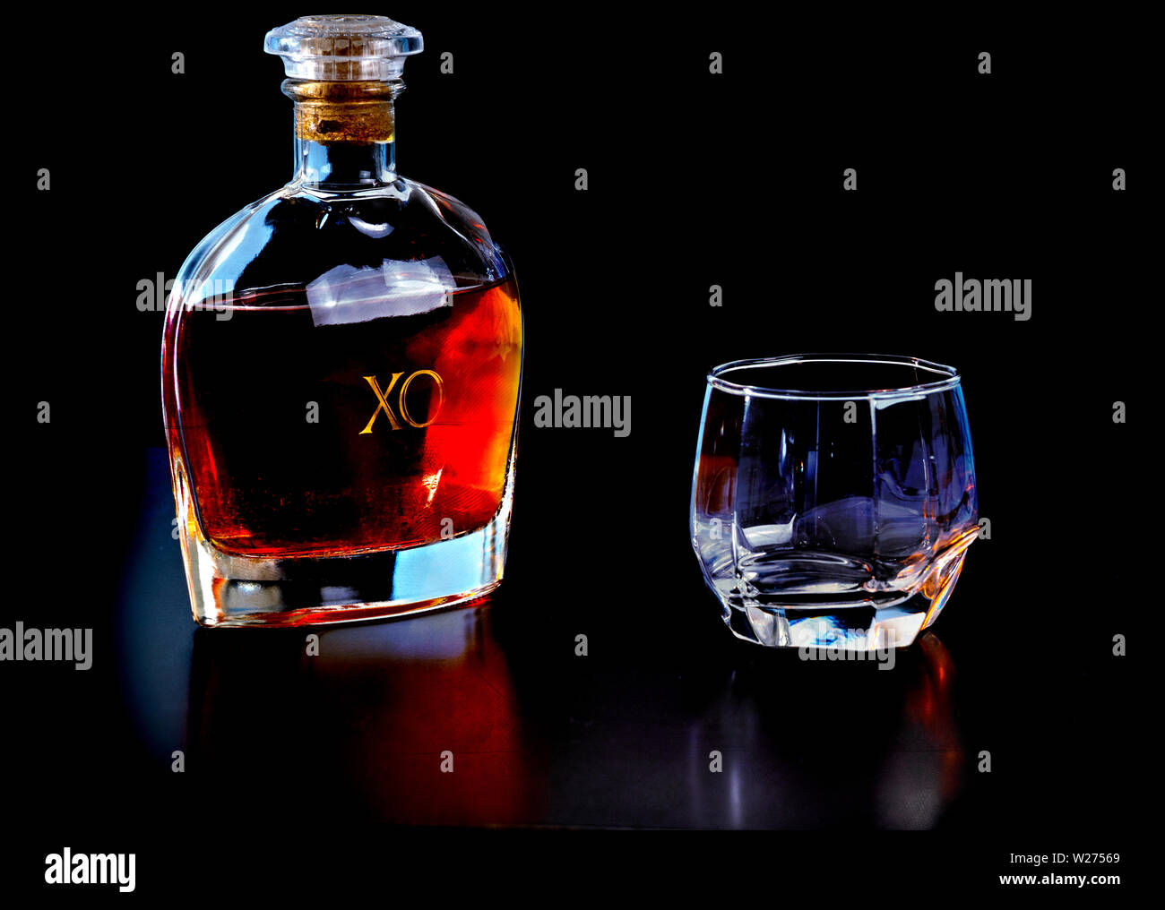 Decanter di maturata cognac francesi con un vetro nero a superficie riflettente con copia spazio sopra Foto Stock