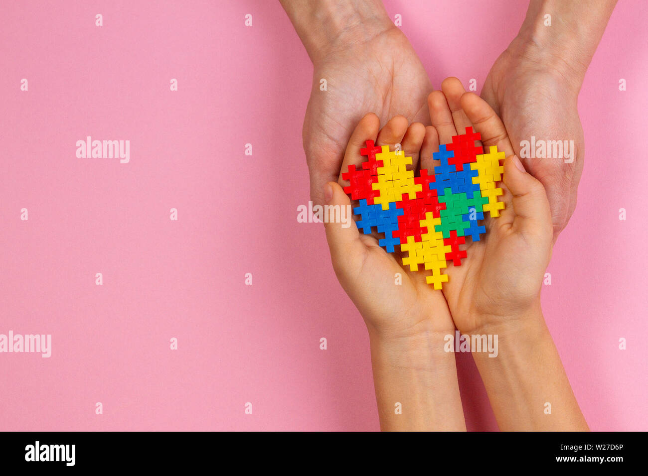 Adulto e bambino mani cuore colorati in rosa chiaro dello sfondo. Mondo autismo consapevolezza giorno di concetto Foto Stock