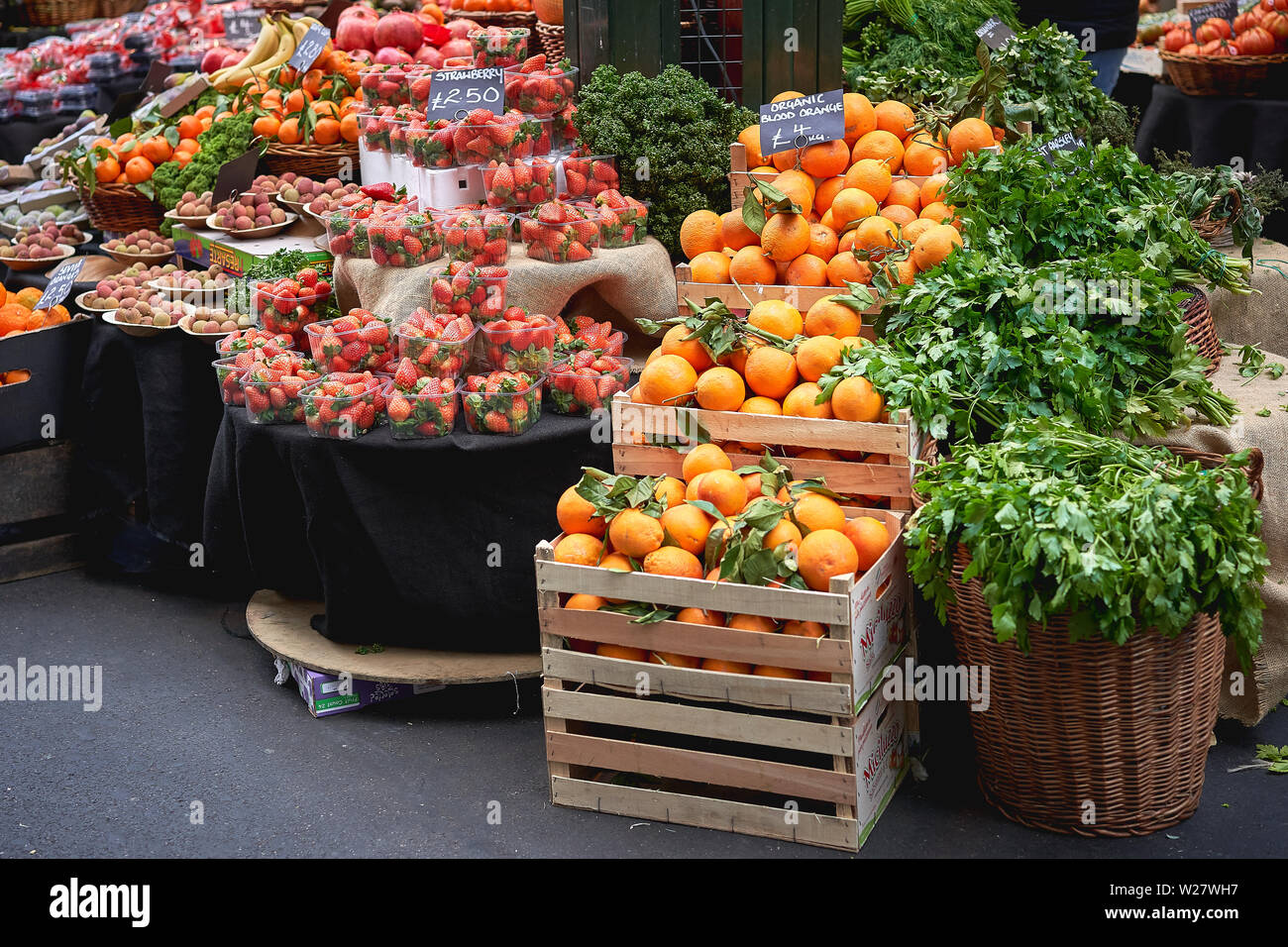 London, Regno Unito - Febbraio, 2019. Verde di generi alimentari comprese le arance, fragole e prezzemolo in vendita su una verdura stallo nella Borough Market. Foto Stock