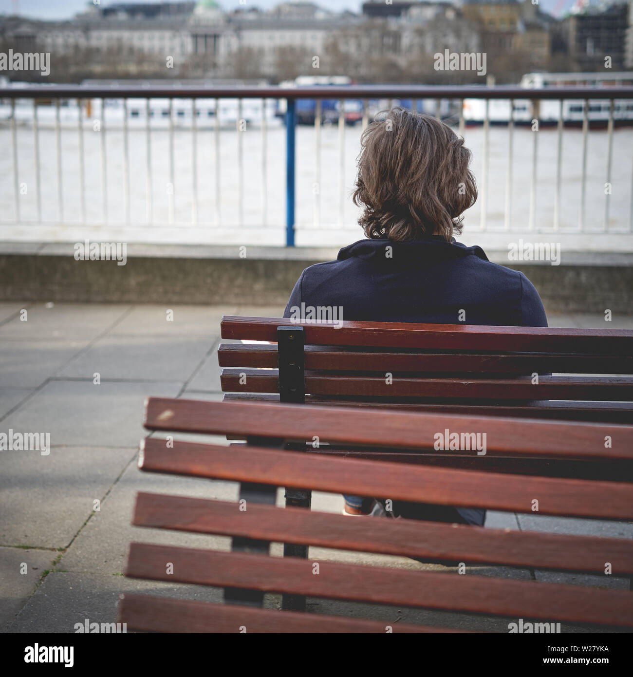 Vista di un uomo solitario seduta su una panchina da dietro. Formato quadrato. Foto Stock