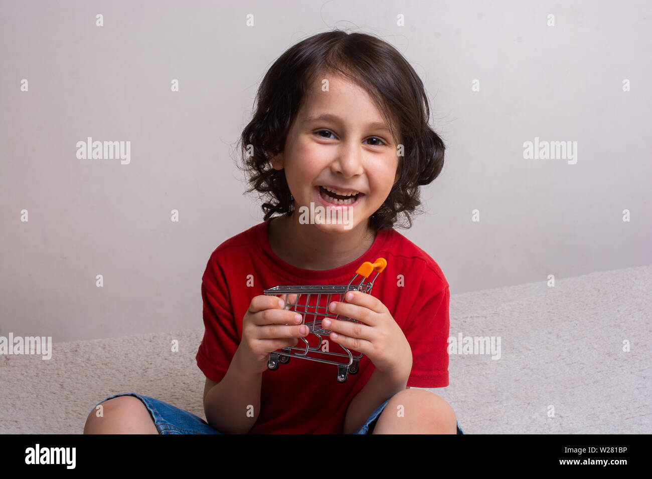 Ritratto di felice piccolo bambino holding miniatura carrello Foto Stock