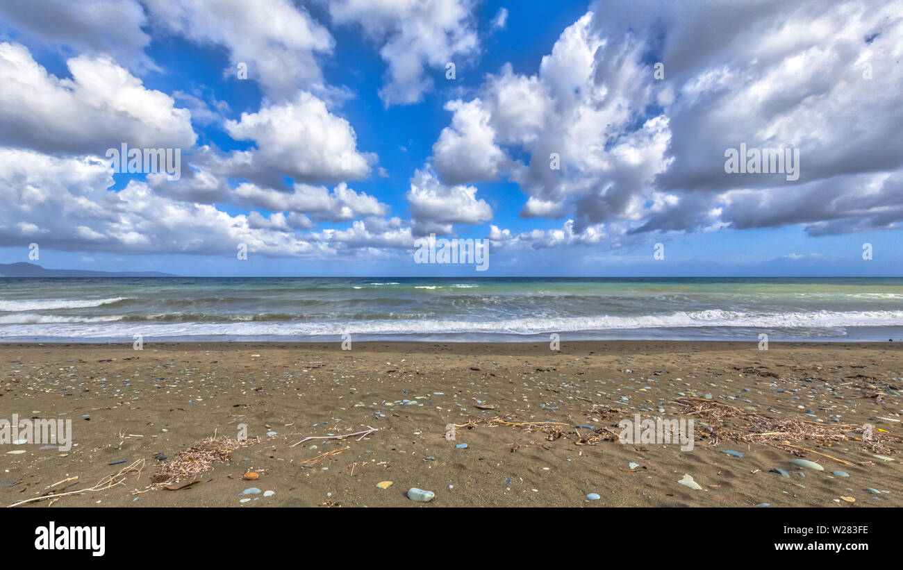 Spiaggia mediterranea con pietre e soffici nuvole sul isola di Cipro Foto Stock