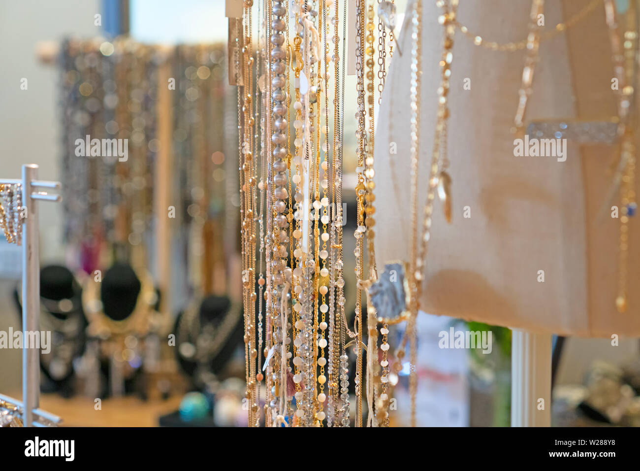 Gioielli in vendita: lunghi filamenti di oro e perle argenteo sul display Foto Stock