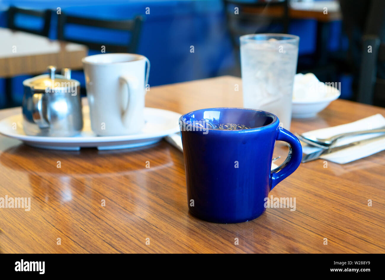 Blue fumante tazza di caffè nero su un tavolo in un caffè Foto Stock
