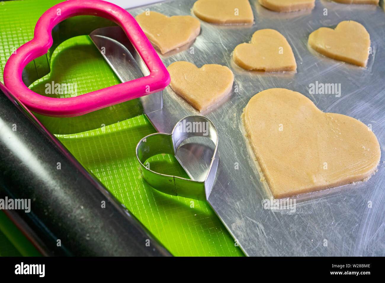 Due a forma di cuore cookie cutters su un cookie teglia; tagliare i cookie in background. Foto Stock