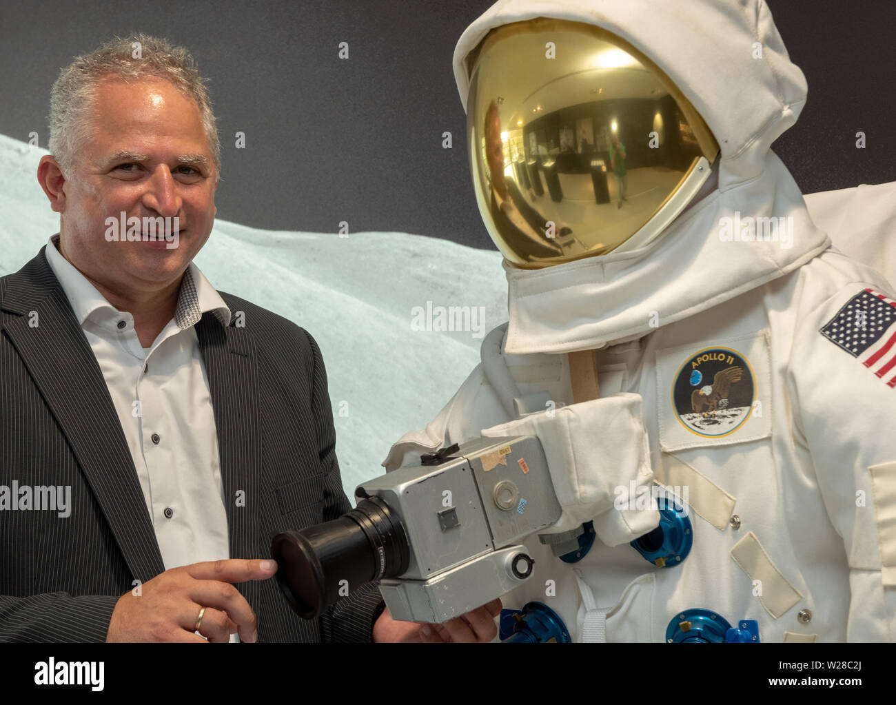 Oberkochen, Germania. 01 Luglio, 2019. Vladan Blahnik, testa lente di sviluppo, sorge accanto ad una tuta spaziale nel Museo Zeiss, il quale è montato con un Hasselblad medio formato fotocamera con un obiettivo Carl Zeiss®. La società sveva sviluppato speciali lenti per la NASA Moonlight Programma, con la quale, tra le altre cose, la prima foto sono state scattate sulla luna nel luglio 1969. (A DPA: 'lenti per la luna" - lenti dell'Apollo voli proveniva dalla Svevia') Credito: Stefan Puchner/dpa/Alamy Live News Foto Stock