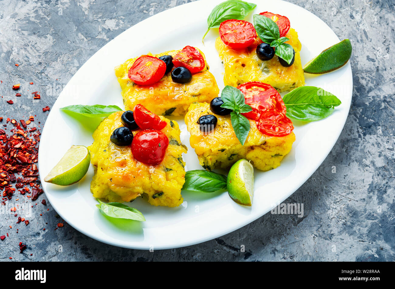 Polenta con pomodori e formaggio.Cucina italiana.Pezzi polenta di granoturco Foto Stock