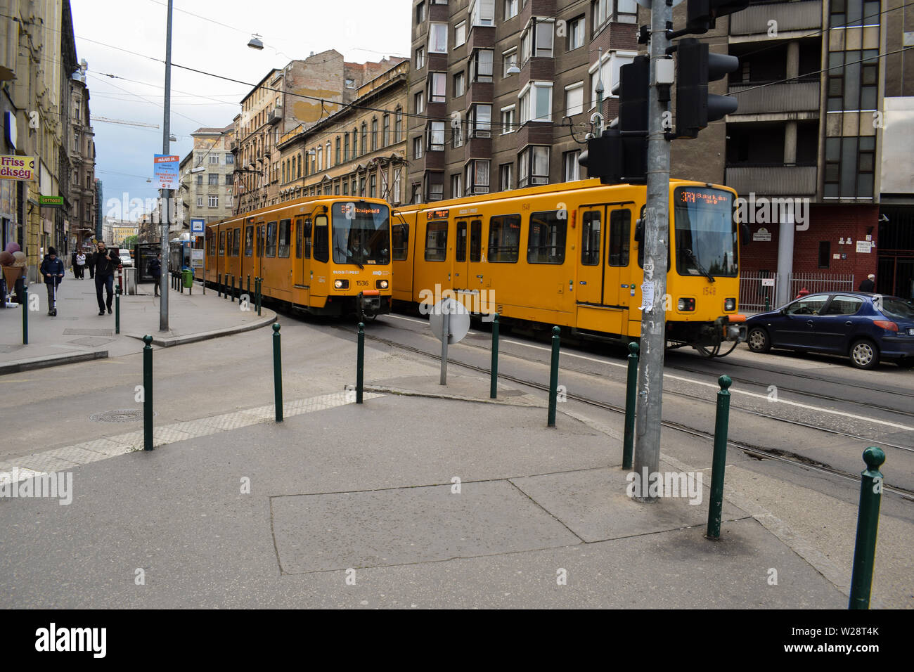 Budapest, Ungheria: Maggio/22/2019 - tram classici mezzi di trasporto della città. Due tram giallo pieno di turisti e persone di andare a lavorare a una guida veloce su t Foto Stock