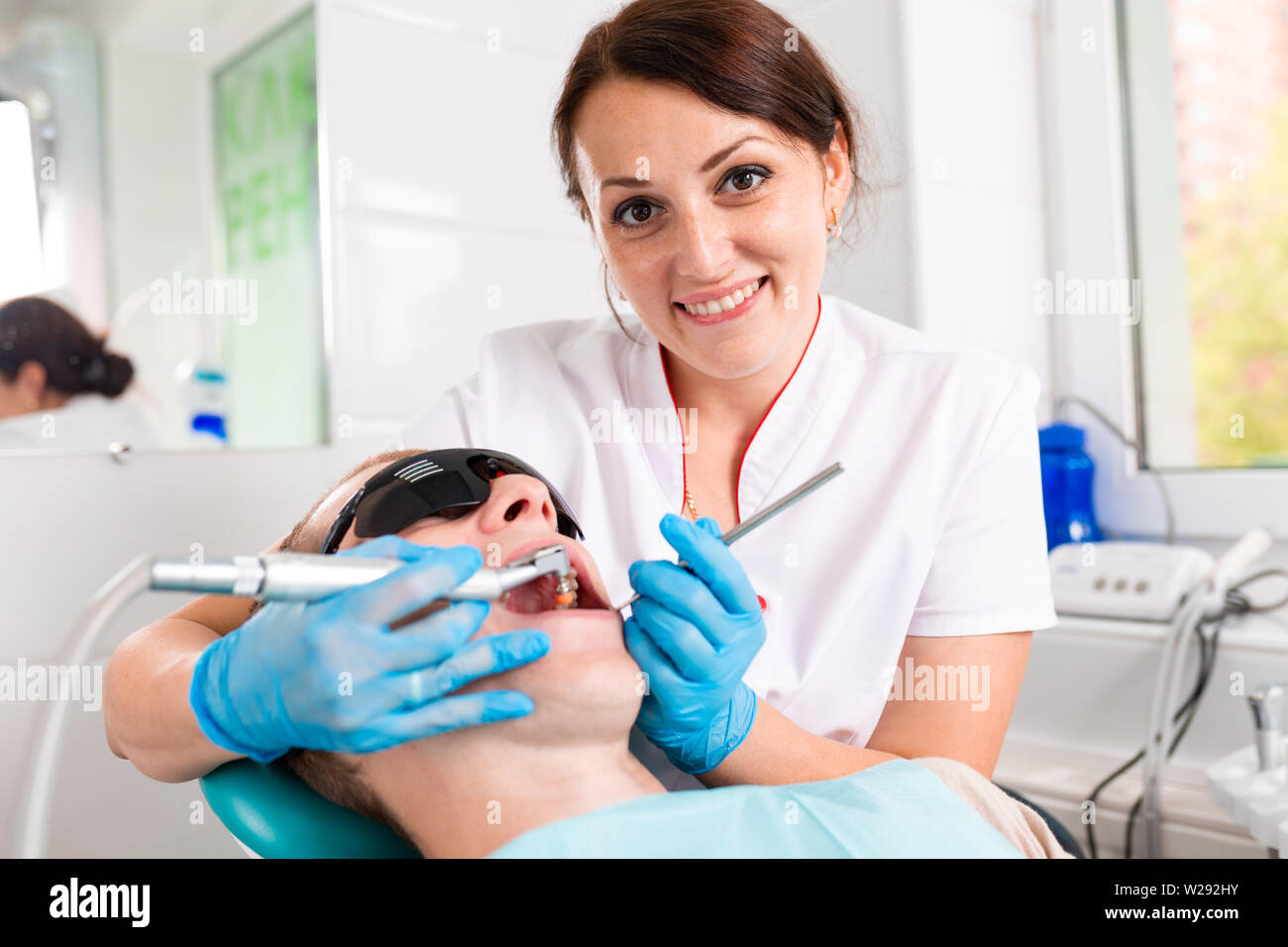 Odontoiatria, dentista considera un dente di un paziente di sesso maschile. La rimozione della carie, installazione di otturazioni sui denti. Foto Stock