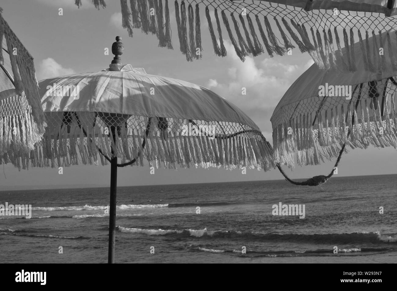 Immagine in bianco e nero di alcuni splendidi design Balinese ombrellone durante il tramonto, decorata con lampadina gialla si illumina e si trova presso la famosa spiaggia di eco Foto Stock