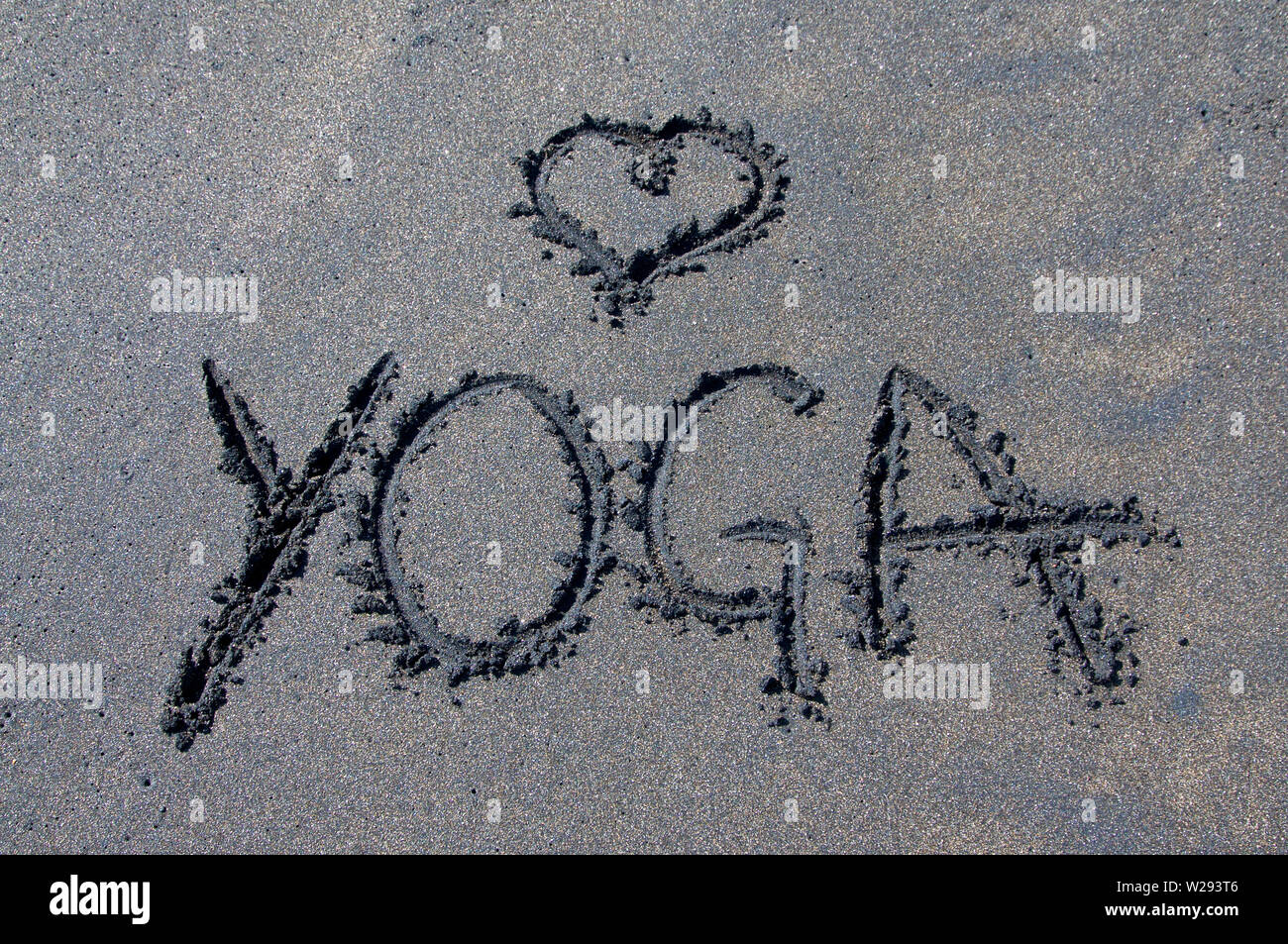 Lo Yoga iscrizione disegnati su una miscela di nero e marrone sabbia in Canggu, Bali - Indonesia Foto Stock