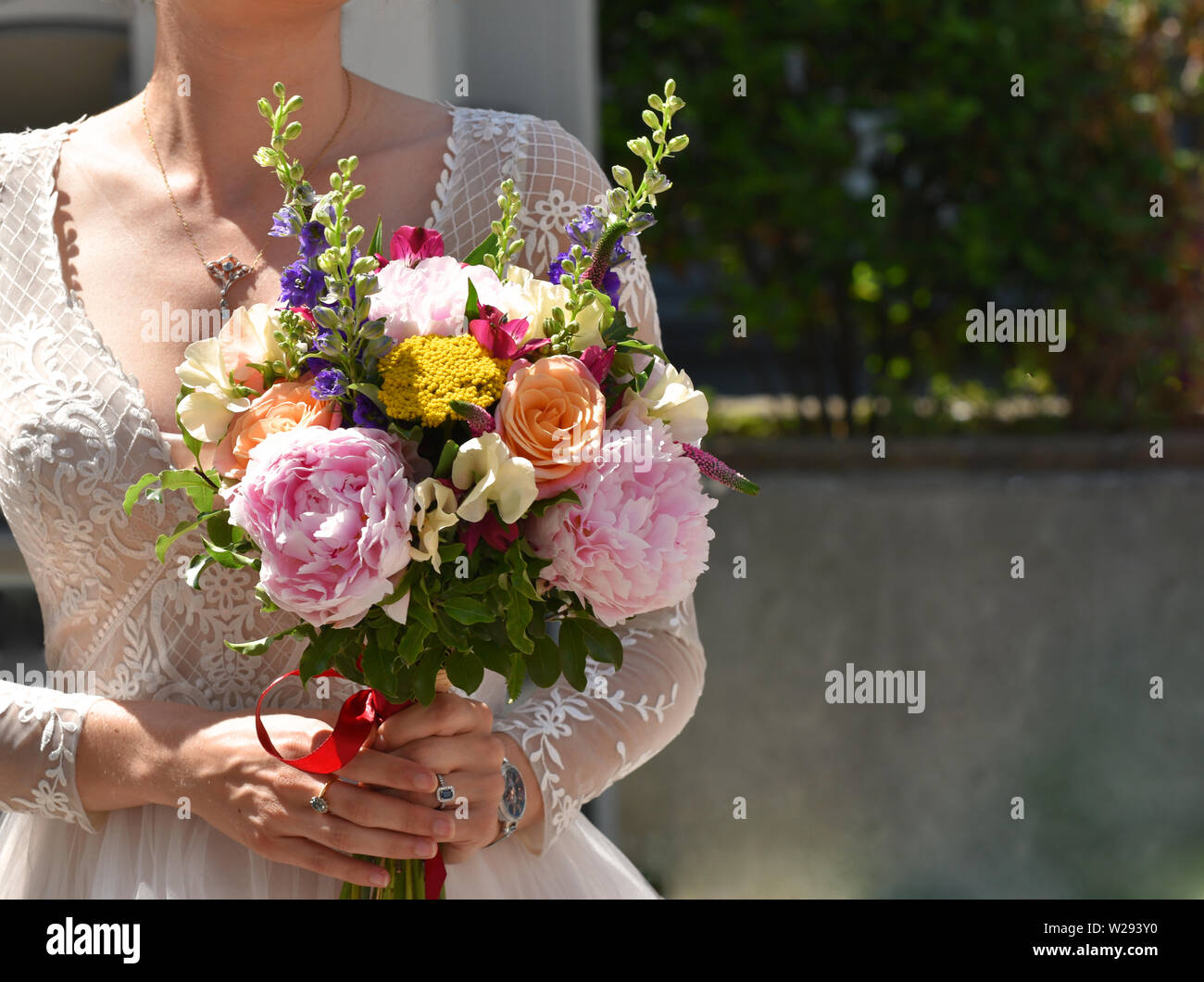 Un tradizionale matrimonio bianco sposa tenendo il suo bouquet sul suo giorno di nozze Foto Stock