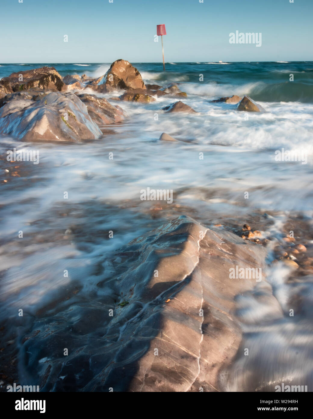 Mare tempestoso con le onde che si infrangono sulle rocce in riva al mare Foto Stock