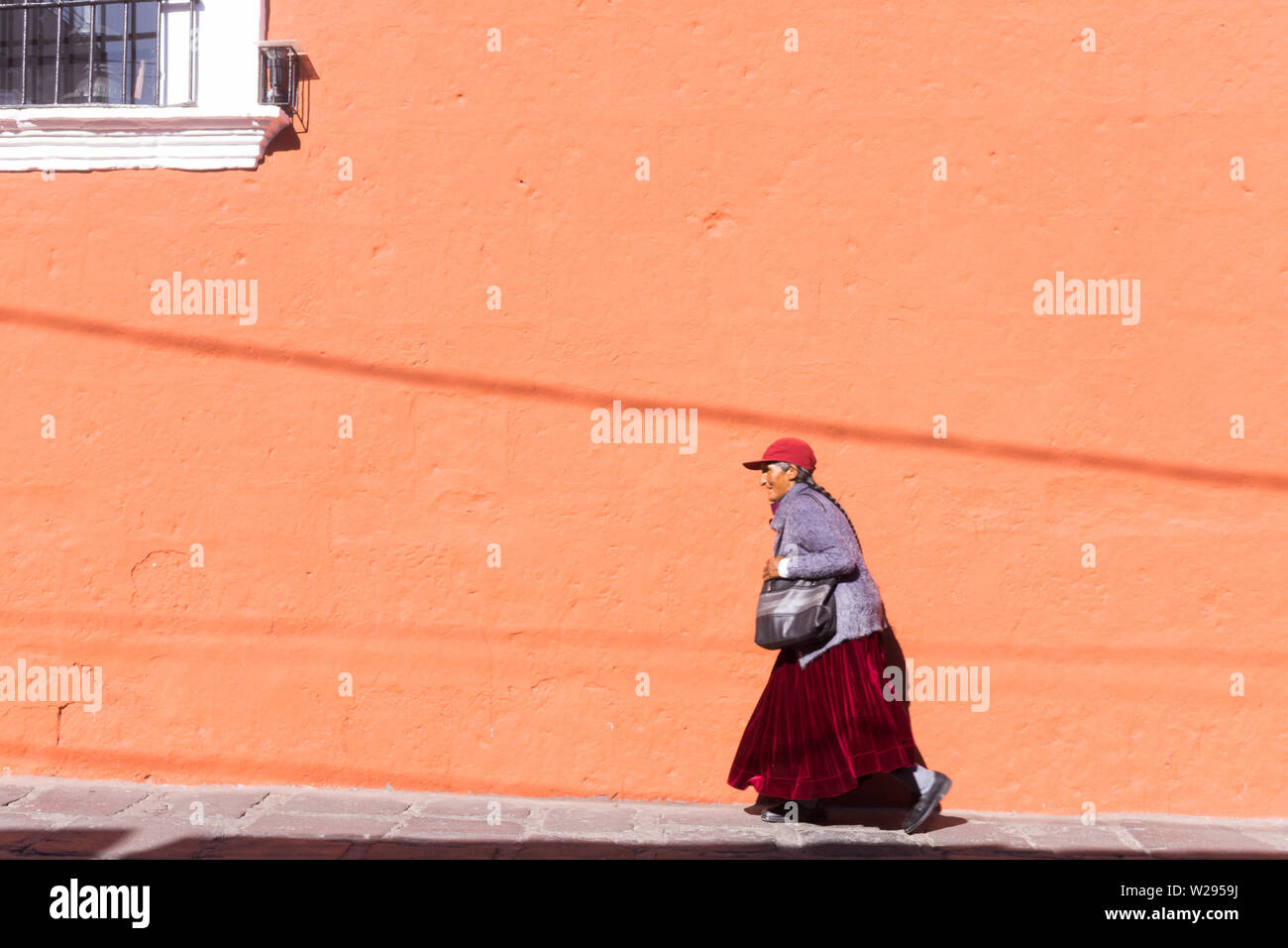 Il Perù donna - una scena di strada di un'anziana donna peruviana a piedi da un color terracotta edificio - Arequipa, Perù, Sud America. Foto Stock