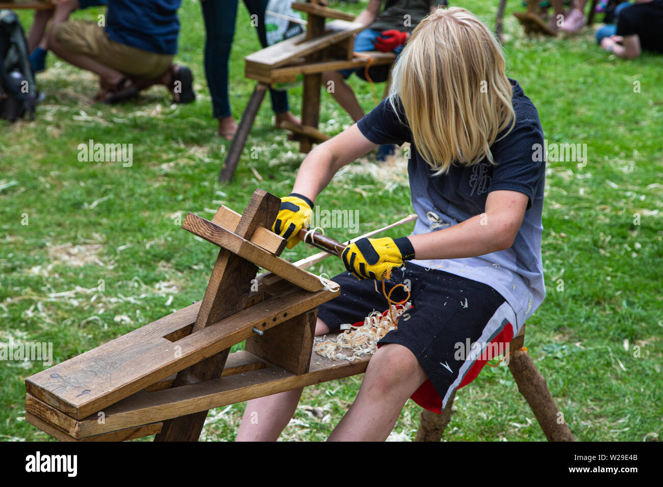 Novantesimo Kent County Show, Detling, 6 luglio 2019. Un ragazzo su un banco per la lavorazione del legno legno whittling. Foto Stock
