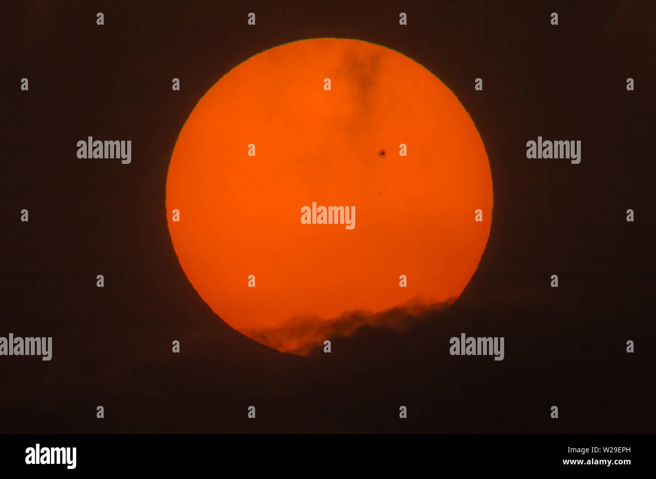 Immagine reale del sole con un grande gruppo di sunspot sopra le nuvole scure dal telescopio di lunghezza focale di 600mm, 2x focale Foto Stock