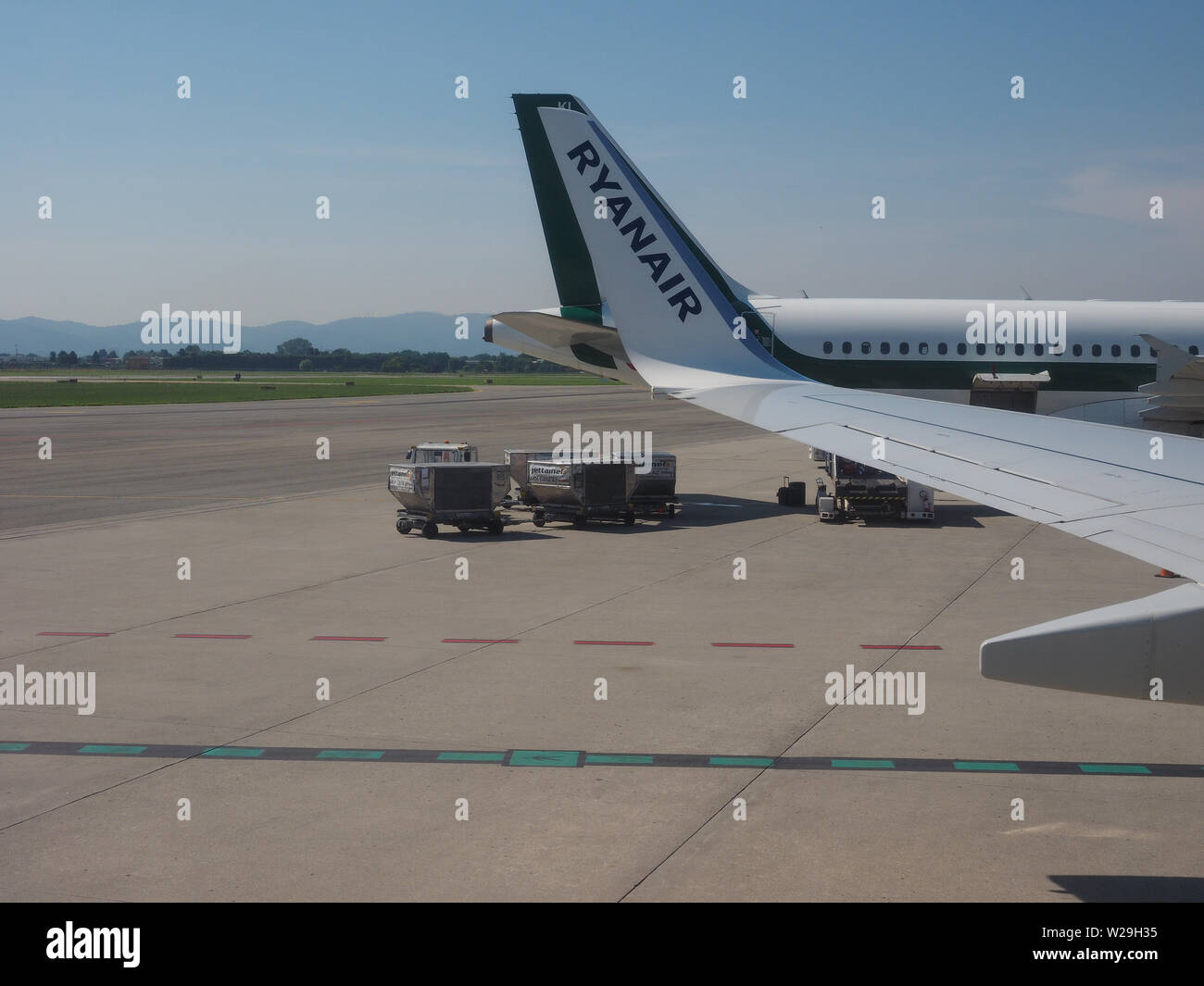 CASELLE, Italia - circa giugno 2019: a terra di aeromobili Servizi di movimentazione merci a Sandro Pertini di Torino aeroporto e aereo Ryanair Foto Stock