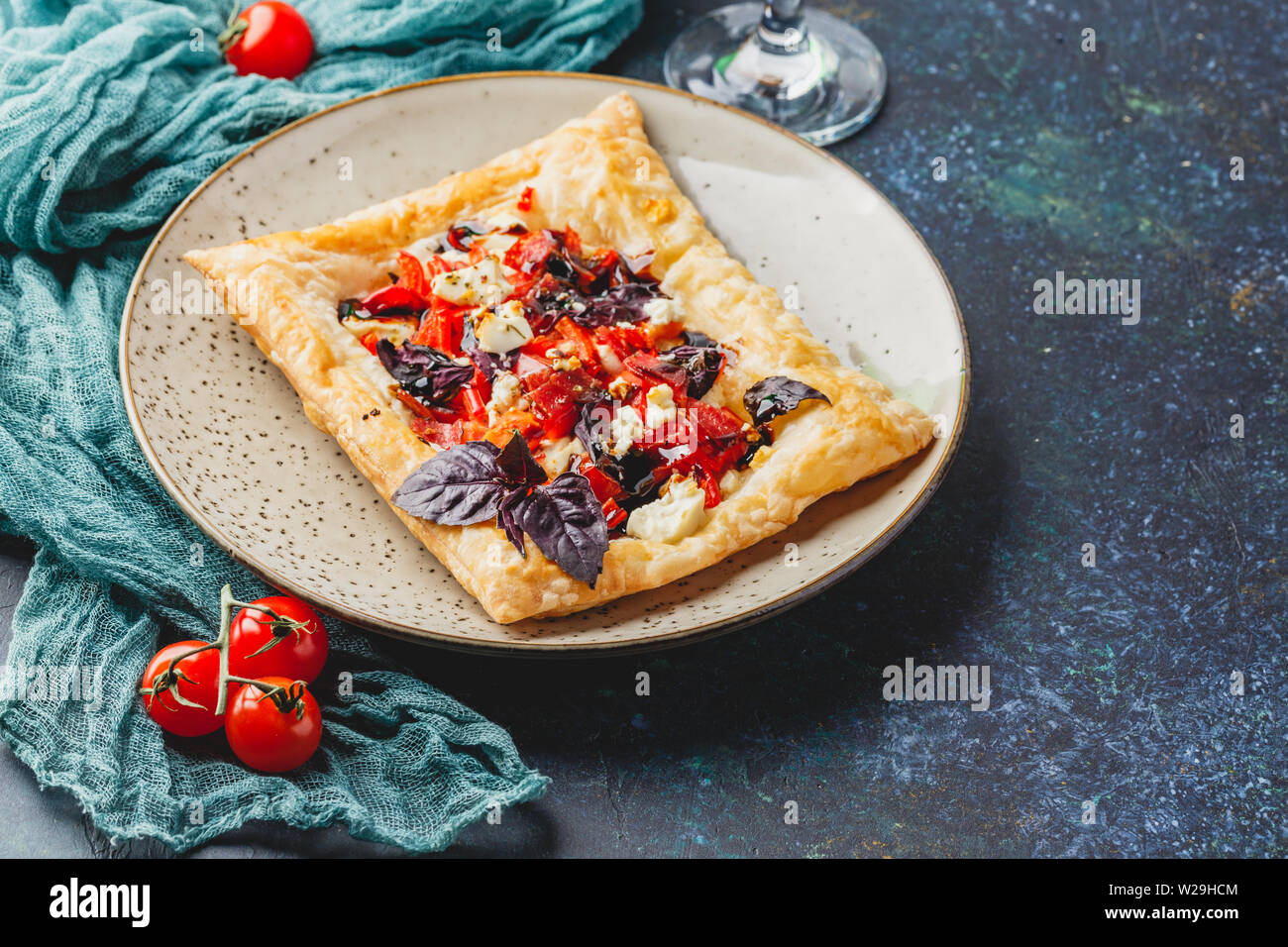 Pasta sfoglia canapes con pomodori, dolci peperoni, salame, formaggio feta e basilico viola. Foto Stock