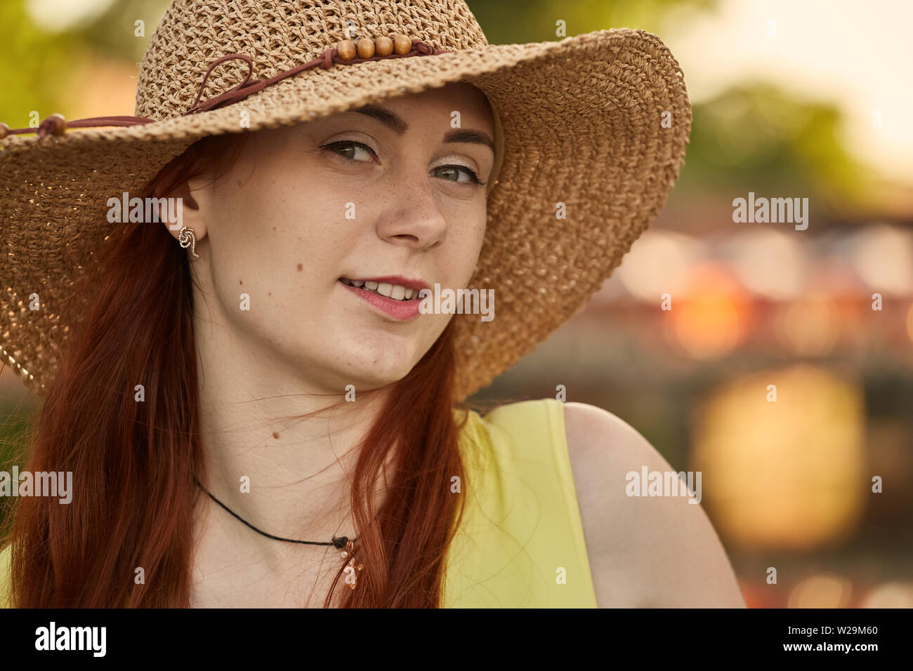 Bella Capelli rossi ragazza nel cappello per il sole guardando la telecamera, sorridente, tonica immagine Foto Stock