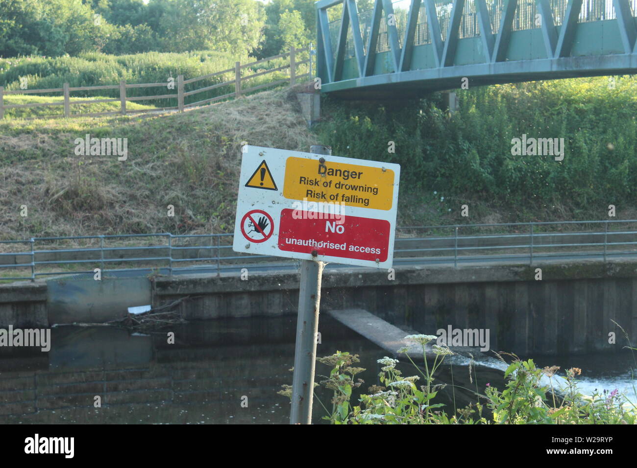 Immagine di "ira, rischio di annegamento' segno di fronte ad un lago, al di sotto di un ponte verde in una giornata di sole nei prati Foto Stock