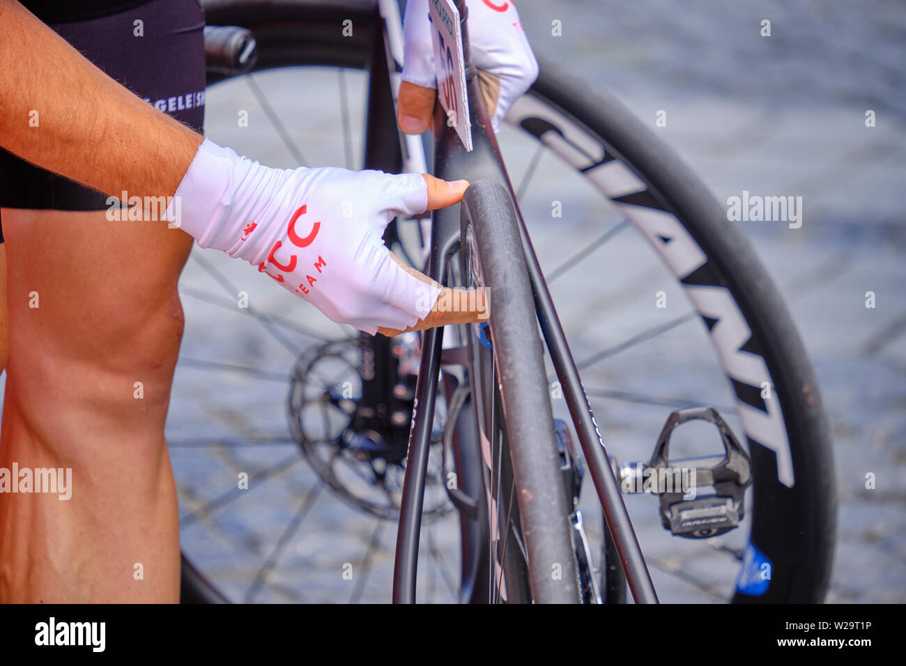 Professional road race ciclista di controllo della pressione dei pneumatici prima di gara. la messa a fuoco a portata di mano e di pneumatico Foto Stock