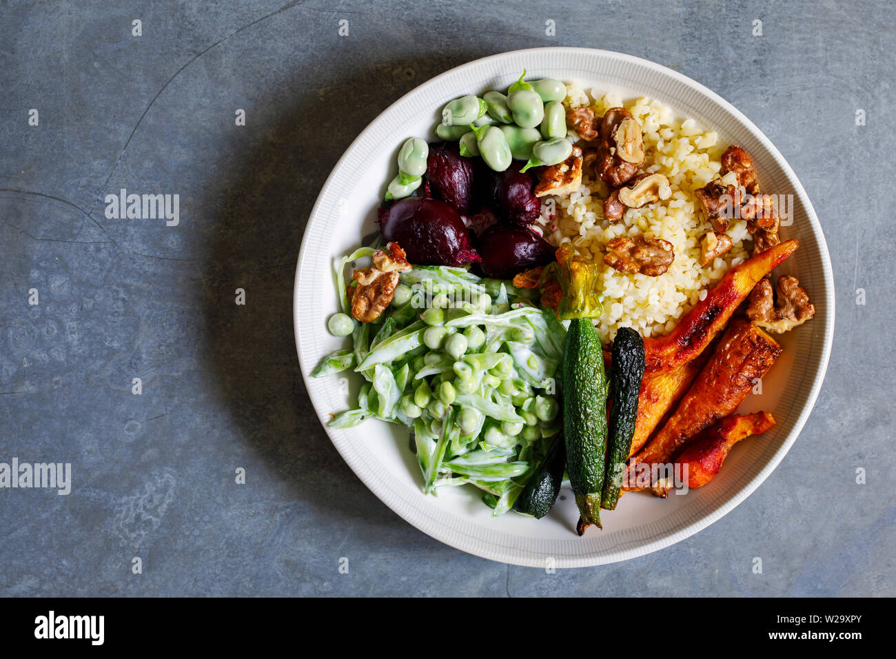 Ciotola di Buddha con arrosti di barbabietole, carote, zucchine e piselli verdi insalata Foto Stock