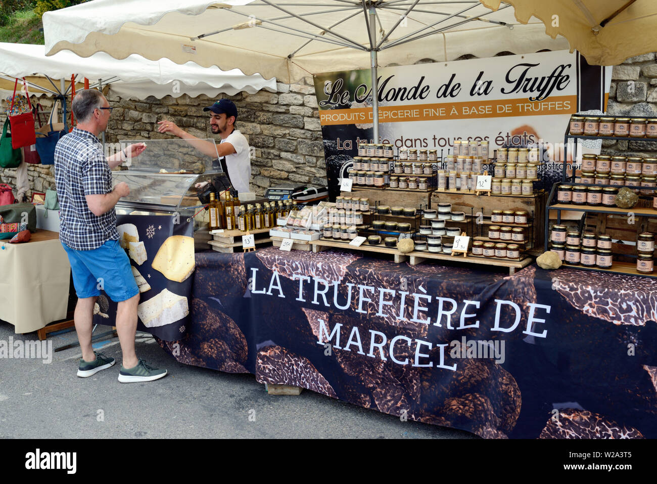 Maschio Middle-Aged turistica tartufo di campionamento formaggio al tartufo di stallo del mercato Bonnieux Luberon Provence Francia Foto Stock