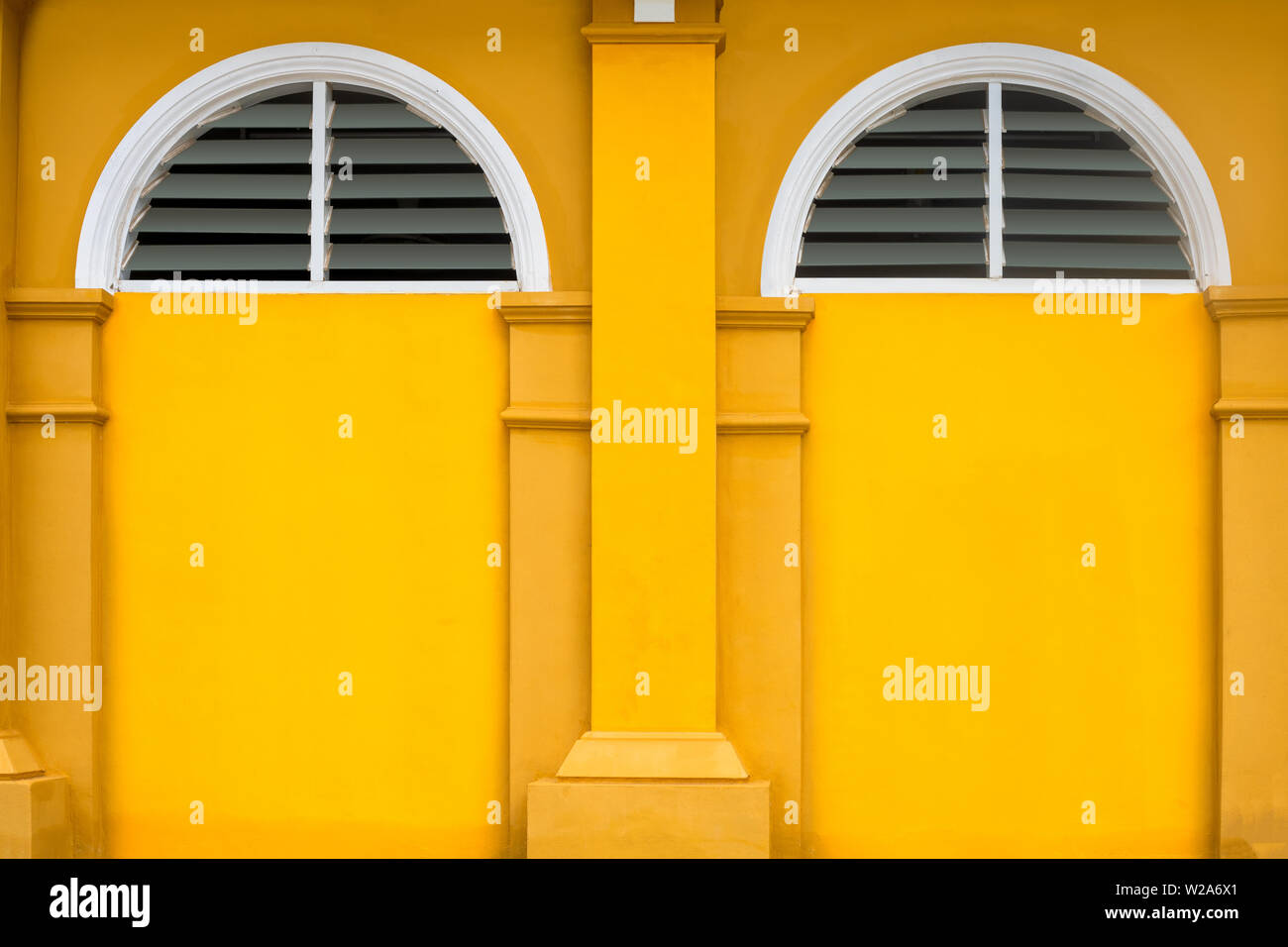 Edificio giallo a parete, edificio giallo e haft finestra cerchio Foto Stock