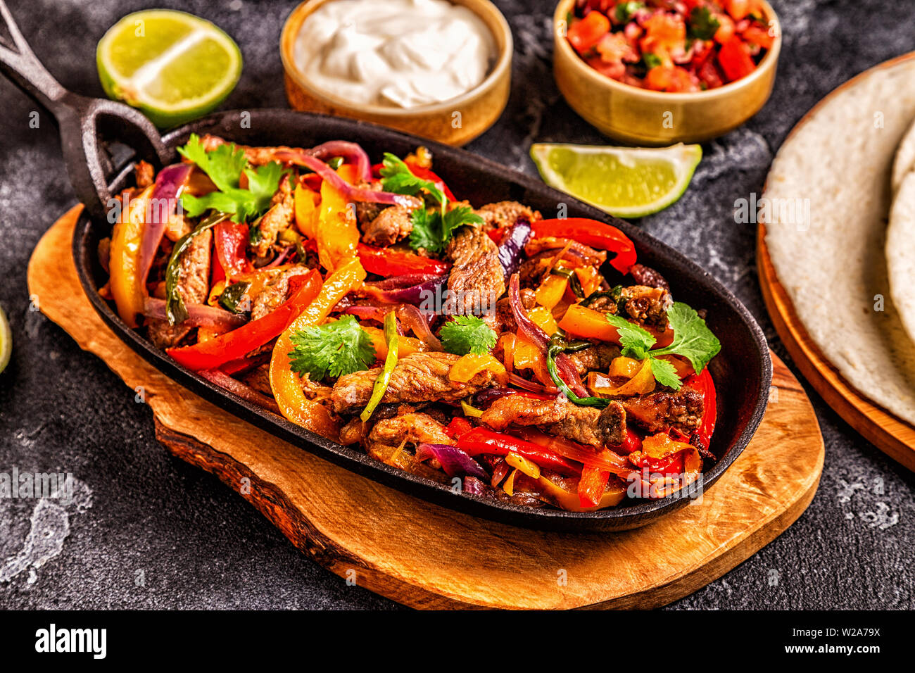 Le FAJITAS colorato con pepe e cipolle, servita con tortillas, salsa e panna acida. Foto Stock