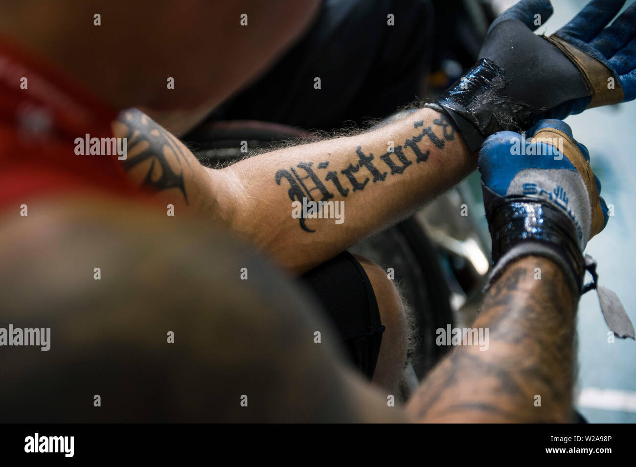 Un braccio tatuato di un giocatore polacco con la parola "Victoria" (vittoria) dopo il gioco.La Nazionale Francese ha battuto i tedeschi, 42:47 durante la finale e ha vinto la Coppa della metropolitana per la seconda volta. La metropolitana Cup è il più grande sedia a rotelle internazionale di Rugby in Polonia. Dal 4 al 6 luglio 2019, la settima edizione di questo evento si è tenuto presso l'Arena Ursynów a Varsavia. Sedia a rotelle il rugby è uno sport paralimpico disciplina per le persone con lesioni del midollo spinale nel tratto cervicale e le persone con disturbi della gamba. Foto Stock