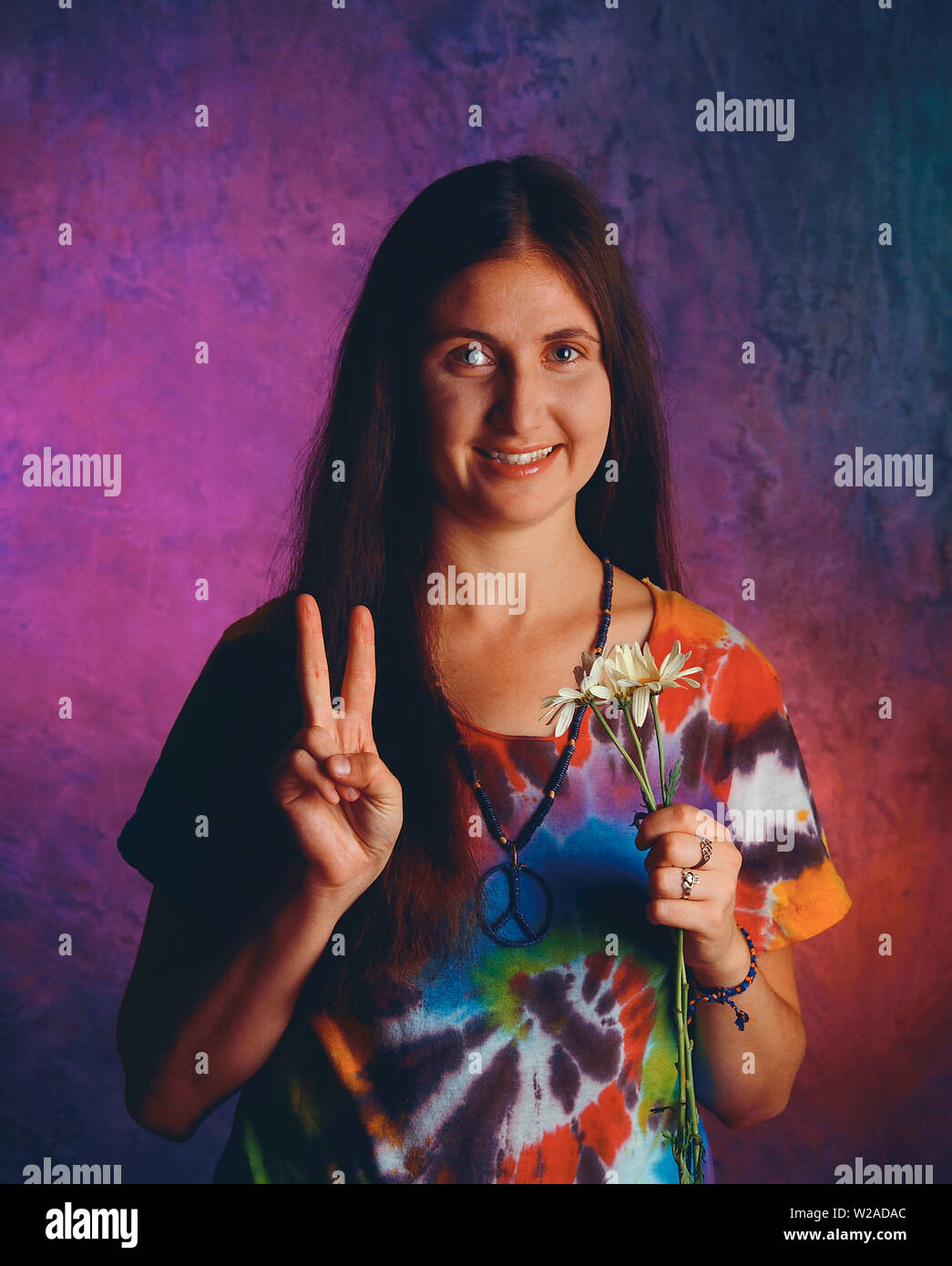 Donna vestita come un hippie tenendo la mano in segno di pace Foto Stock