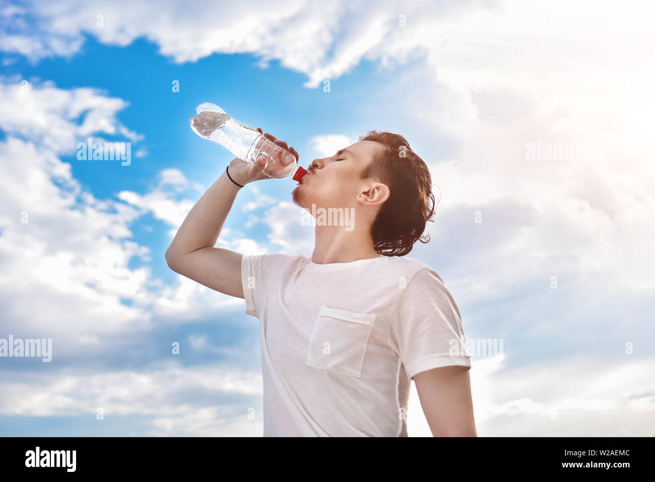 Giovane ragazzo beve acqua fresca contro del lago e la foresta sfondo. estate sete. Bella vista Foto Stock