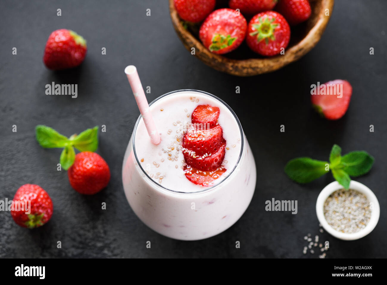 Frullato fragole frullato o in vetro con semi di Chia e rosa cannuccia su sfondo nero Foto Stock