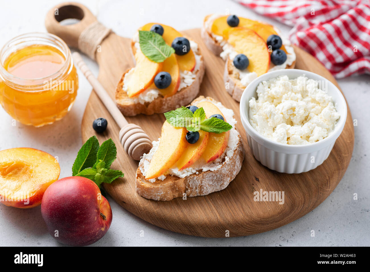 Frutta, Miele e ricotta bruschetta sulla tavola di legno. Gustosa estate sano antipasto o uno spuntino per picnic Foto Stock