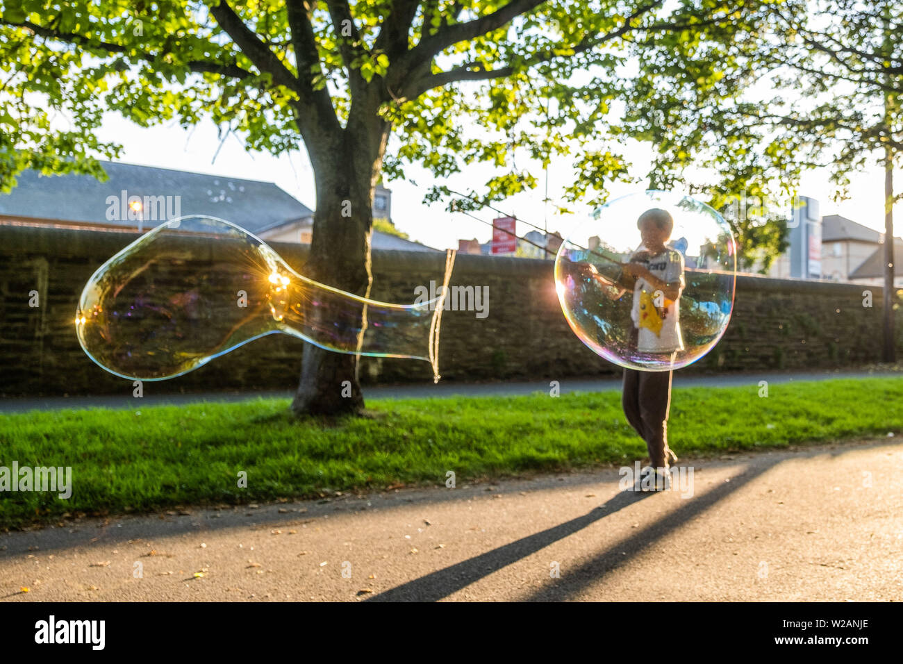 Aberystwyth Wales UK, domenica 07 luglio 2019 UK Meteo: una famiglia nel parco di Aberystwyth divertirsi facendo e giocando con bolla di sapone gigante in serata sole alla fine di una calda giornata d'estate nel Galles occidentale. Photo credit: Keith Morris/Alamy Live News Foto Stock