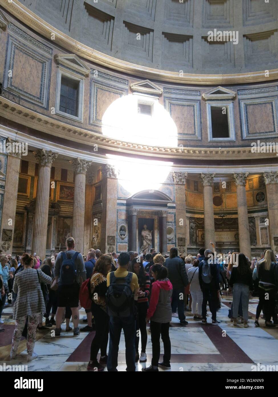 Visitando la folla ammirare l'architettura romana dell'interno del Pantheon quando la cupola aperta getta una circolare per la riflessione della luce solare sulla parete. Foto Stock